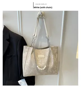 Detail view of cream floral tote bag with chain strap and elegant pearl charm accessory