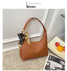 Detail of a brown lychee pattern half-moon bag featuring a silk scarf on the shoulder strap
