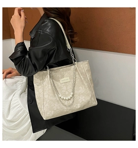 Detail of floral embossed tote bag with elegant pearl and metal chain shoulder straps