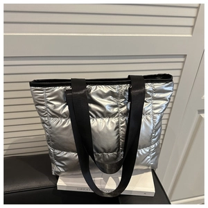 Detailed close-up of metallic silver quilted tote bag with black strap and puffy texture