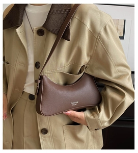 Macro detail of brown litchi pattern leather underarm bag with crescent moon shape design