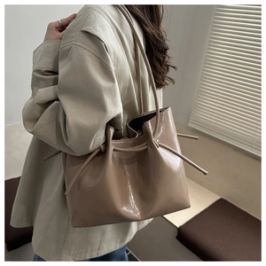 Dettaglio del nodo coulisse sulla borsa tote in pelle verniciata lucida color caffè chiaro