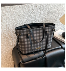 Detail of checkered tote bag with gold logo, metal buckle and leather handles