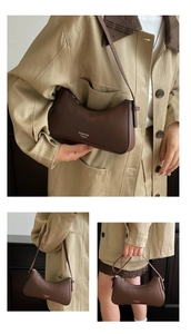 Macro shot of dark brown lychee grain leather underarm bag with elegant brand logo detail