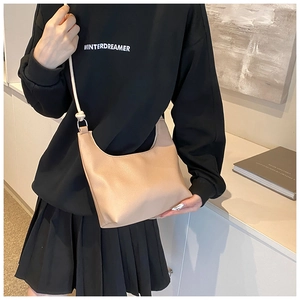 Detail view of the beige crescent tote bag showing smooth leather texture and strap nodes