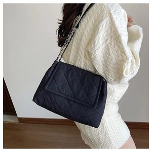 Close-up of black quilted chain shoulder bag featuring puffy fabric and chic leather strap