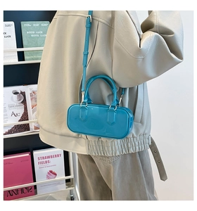Detail of bright blue glossy patent leather crossbody bag with adjustable shoulder strap