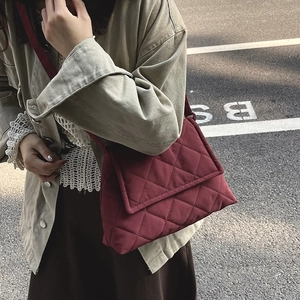 Quilted wine red crossbody bag with chain strap shown on model during autumn