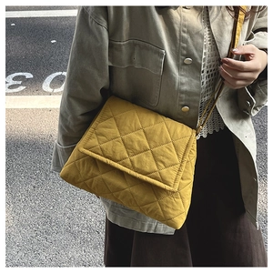 Detail of yellow quilted nylon shoulder bag showing puffy diamond stitching and flap closure