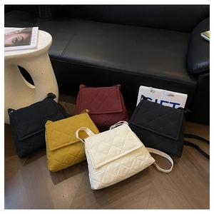 Close-up of quilted cross-body bags in black, burgundy, yellow, and beige on wooden floor