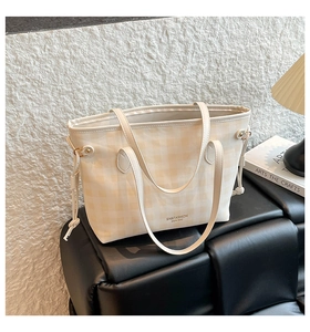 Plaid tote bag on a bench next to a vintage lamp and books in a lifestyle setting