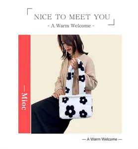 Plush white shoulder bag with black floral patterns worn with an autumn outfit