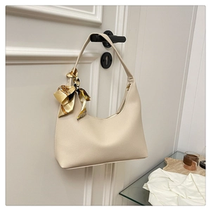 Close-up of beige crescent bag with lychee grain texture and elegant silk scarf detail