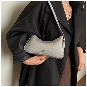Close-up of silver lychee grain leather shoulder bag worn with a black trench coat