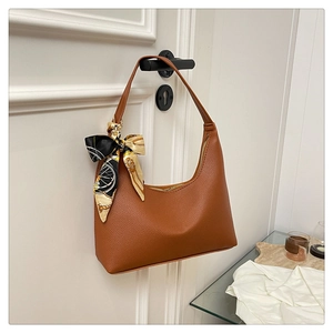 Detail of brown lychee texture hobo bag with a decorative floral silk scarf on a door