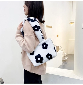 Detail of plush tote bag with black flower pattern worn by model on shoulder