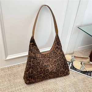 Large leopard print tote bag with brown leather strap on a textured white carpet