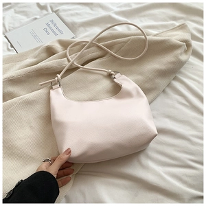 Detail of soft cream PU leather hobo bag with pebble texture on minimalist knit background