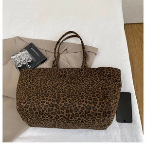 Detail of leopard print canvas tote bag on white sheets with casual lifestyle styling