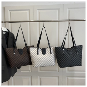 Detailed close-up of textured monogram tote bags in brown, beige, and black colors