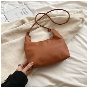 Close-up of brown pebbled leather hobo bag with stylish knotted shoulder strap detail