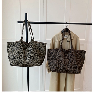 Detail of leopard print canvas tote bags in light and dark brown hanging on a metal rack