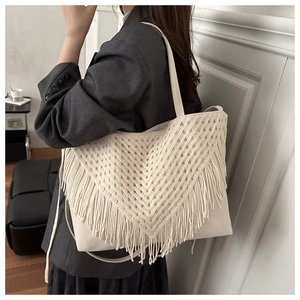 Detailed macro view of bohemian macrame tassels on a cream leather tote bag for women