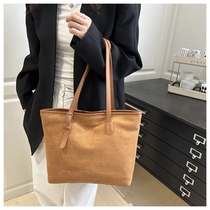 Detail of tan suede tote bag with slender straps and buckle adjustment on shoulder