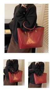 Detail view of large dark red patent leather tote bag with elegant gold metal hardware