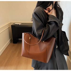 Detalle del bolso tote de cuero marrón con gran capacidad y herrajes de metal dorado