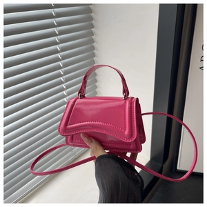 Detail of hot pink patent leather hourglass handbag with shiny mirror finish and handle