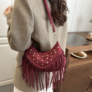 Borsa a spalla in camoscio bordeaux con frange e borchie dorate in un interno minimalista