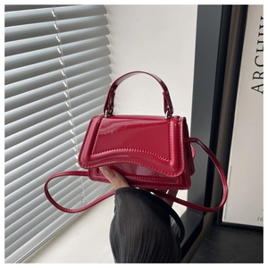 Detail view of the red glossy patent leather mini bag with curved hourglass base