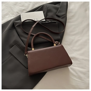 Detail of a dark brown retro crossbody bag featuring golden hardware and a leather handle
