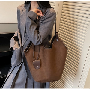 Close-up of a large dark brown suede tote bag with a minimalist shoulder strap and charm