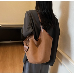 Detailed back view of a large brown faux suede tote bag worn as a shoulder bag