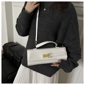 Detail of white crocodile texture handbag featuring golden turn-lock and detachable strap