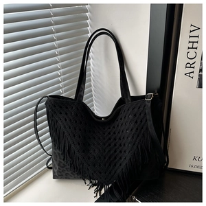 Close-up of black hollow crochet tote bag with fringe details and woven patterns