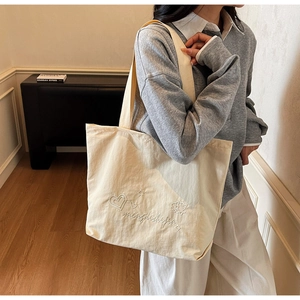Detail of white embroidery and heart pattern on a large beige canvas tote bag