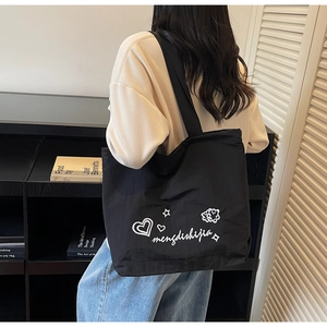 Detail of a large black canvas tote bag with white hand-drawn heart and star patterns