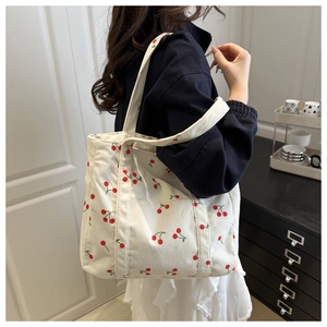 Détail du sac fourre-tout en velours blanc avec motif cerise et large bandoulière