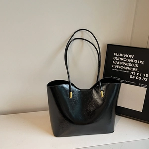 Glossy black faux leather tote bag with thin shoulder straps and gold hardware details