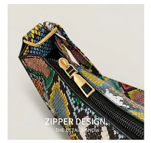 Detail showing the golden metal zipper and vibrant snakeskin texture on the handbag