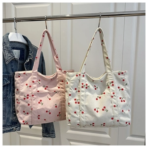 Détail de sacs cabas en velours côtelé rose et blanc avec imprimés cerises et poche frontale