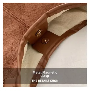 Close-up of golden magnetic snap button on brown suede bag with premium stitching