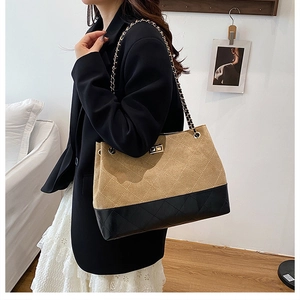 Detail of quilted tote bag with khaki suede and black leather patchwork and gold chain strap