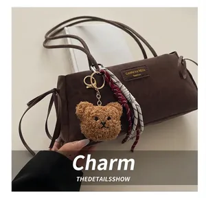 Detailed close-up of brown faux leather shoulder bag with plush bear charm and bow detail