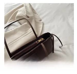 Close-up of smooth gold metal zipper and branded logo detail on brown velvet underarm bag