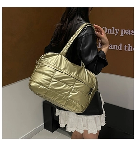 Detailed close-up of metallic gold puffer tote bag featuring square quilted stitching details