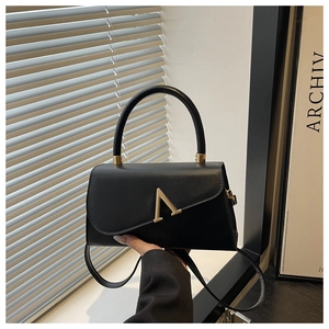 Detail of black leather handbag with elegant gold V-shape clasp and smooth finish